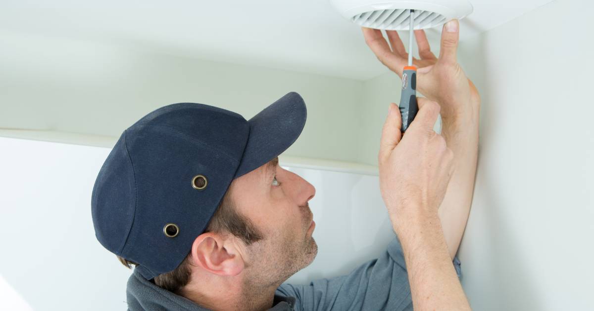 homme installant une VMC électrique sur un plafond